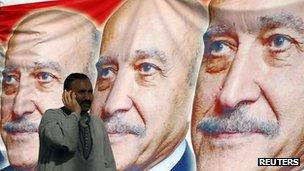 A man stands in front of images of Gen Suleiman at a campaign gathering, 6 April 2012