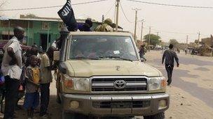 In this Saturday, 14 April, 2012 photo, fighters from the Ansar Dine group, flying the group's black flag, instruct local residents in how to follow Shariah, as they stop in a market area of Timbuktu, Mali.