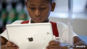 A young boy looks at an Apple iPad