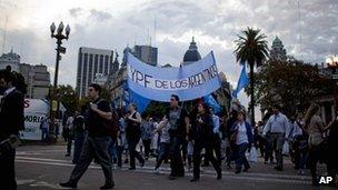 Demonstrators carrying a flag with the words 'YPF belongs to the Argentines'