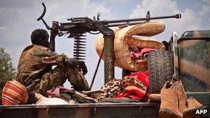 South Sudanese soldier sitting next to a machine gun