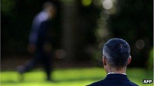 Secret Service agent watches as President Barack Obama walks in the White House grounds, 27 April 2012