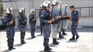 Palestinian women police officers stand behind policemen with riot shields in training