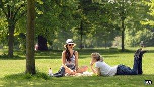 Two women relax in the sunshine in Hyde Park in London
