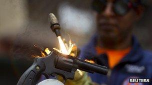 A worker destroys a weapon confiscated by the police during a news conference in Caracas May 18 2012.