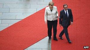 German Chancellor Angela Merkel guides new French President Francois Hollande on the red carpet