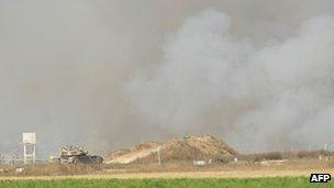 Smoke billows from the Gaza Strip as an Israeli tank monitors the border area after the firefight