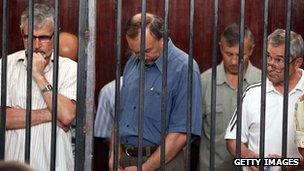 Some of the 24 men found guilty of being mercenaries are seen standing behind bars during their trial in Tripoli