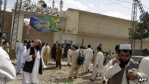 People gather outside a madrassa where a blast killed 15 people