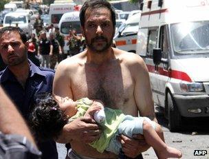 A man carries an injured child after a blast in Qudssaya, Damascus, 8 June
