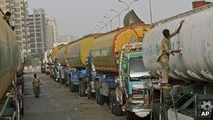 A Pakistani man, right, paints an oil tanker, which was used to transport NATO fuel supplies to Afghanistan