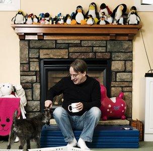 Linus Torvalds sitting bellow penguin collection