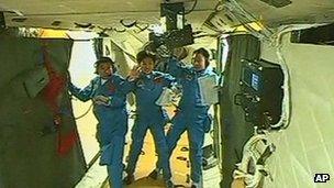 The three Chinese astronauts waving to cameras from Tiangong 1 space lab