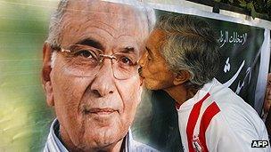A supporter of Mr Shafiq kisses a poster bearing his image