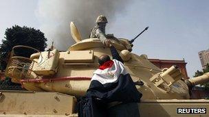 A protester wearing an Egyptian flag reaches to shake hands with a soldier in a tank, Cairo - 29 Jan 2011