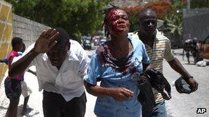 Bleeding woman is led to an ambulance after being hit by a stone during a demonstration in Port-au-Prince