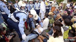 Police try to move a protester at the Ohi nuclear plant in Japan on 1 July 2012