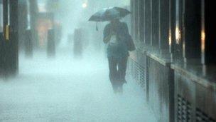 Woman walks with umbrella in heavy rain