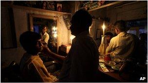 A man has a haircut by candle light in Calcutta, India (31 July 2012)