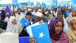 Somali delegates hold up the book of the constitution on July 25, 2012 during the National Constituent Assembly meeting in Mogadishu