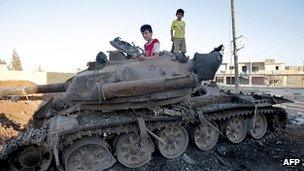 Children play on an abandoned tank close to the city of Aleppo