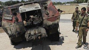 Israeli soldiers stand next to a burnt-out Egyptian armoured personnel carrier captured by gunmen who attacked a border post at Kerem Shalom late on 5 August 2010