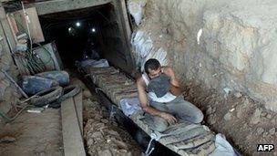 Palestinian men transport bags of cement through tunnels used for smuggling goods on 23 August