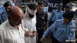 Pakistani police officers escort blindfolded Muslim cleric Khalid Chishti to appear in court in Islamabad