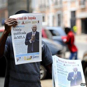 Street-seller in Luanda holds up copy of the state-owned Jornal de Angola daily on 2 August