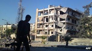 A photo purportedly showing a rebel fighter walks past a damaged building in Aleppo (2 September 2012)