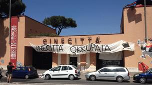 A strike banner hangs over an entrance to the Cinecitta studios