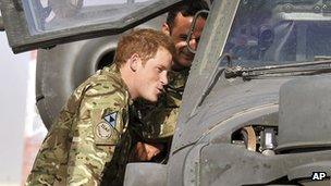 Prince Harry examining the cockpit of an Apache helicopter with a member of his squadron