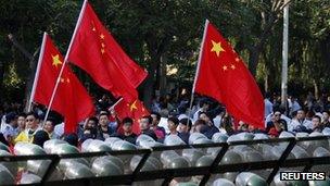 Protesters wave Chinese flags while marching outside Japanese embassy during a protest in Beijing