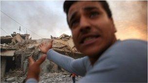 A man points towards a bombed house in Aleppo, Syria