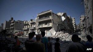 Syrian men look at the destroyed building of a school which was bombed by Syrian government war planes which was allegedly housing rebel fighters in the Bustan al-Qasr neighbourhood of Aleppo