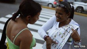 A supporter of Henrique Capriles shows a sample ballot to a woman