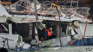 A fireman inspects the back end of the badly damaged Lamma IV passenger boat after a collision, near the shores of Hong Kong"s Lamma island on 3 October, 2012 the morning after it was pulled out of the waters following its sinking on 1 October