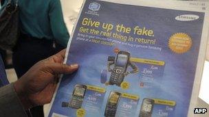 A Kenyan mobile phone seller poses on 1 October 2012 in Nairobi with an advert about fake phones