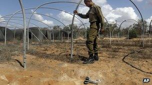An Israeli soldier inspects a field where a mortar fell near the Israel-Gaza border (8 October 2012)