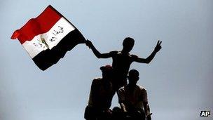 Protesters wave the Egyptian national flag as they perch on top of a street lamp in Tahrir Square in Cairo, Egypt (July 2011)