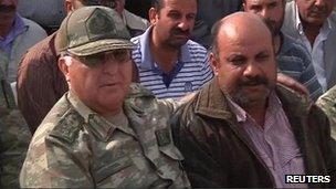 General Ozel with arm around man who's wife and children were killed