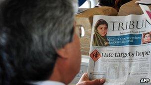 A Pakistani passenger reads a local newspaper featuring news of Malala Yousafzai