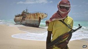 Somali pirate Hassan stands near a Taiwanese fishing vessel that washed up on shore after the pirates were paid a ransom and released the crew, Hoboyo, Somalia 23 September 2012