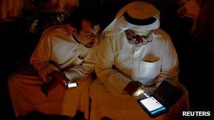 Kuwaitis check their messages at a sit-down protest in Kuwait City, 19 October