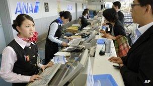 Employees deal with passengers at the counter at Sendai Airport in Sendai, northern Japan after flights in and out of the airport were cancelled 30 October, 2012