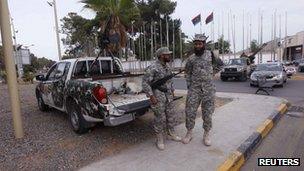 Two soldiers stand guard beside an armed pick-up truck outside the Libyan General National Congress