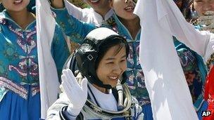 China's first female astronaut Liu Yang waves during a sending-off ceremony as she departs for the Shenzhou 9 spacecraft rocket launch pad (16 June 2012)