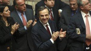 Greece's Prime Minister Antonis Samaras and his party's lawmakers of the New Democracy applaud after voting on the country's 2013 budget
