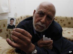 The father of Qais Omari holds up a photo of his son (15 November 2012)