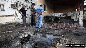 Israeli civilians inspect the damage to a house in Ofakim